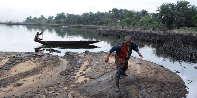 A man walks on slippery spilled crude oil on the shores of the Niger Delta swamps of Bodo on June 24, 2010.