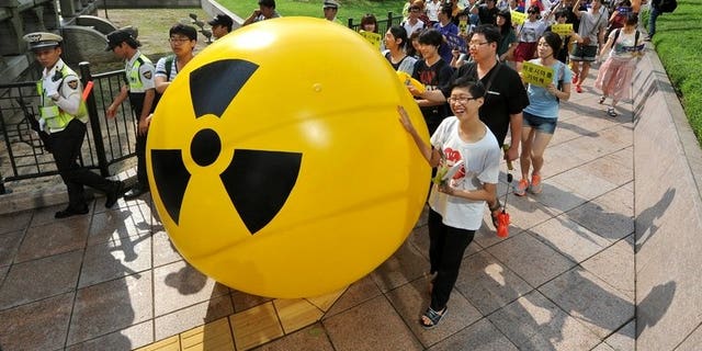 South Korean activists march while rolling a large balloon with a radioactivity warning sign during an anti-nuclear protest in Seoul on August 6, 2013. A former deputy minister has been charged with taking bribes as part of a corruption probe into South Korea's nuclear industry which has already indicted nearly 100 people, prosecutors said Tuesday.