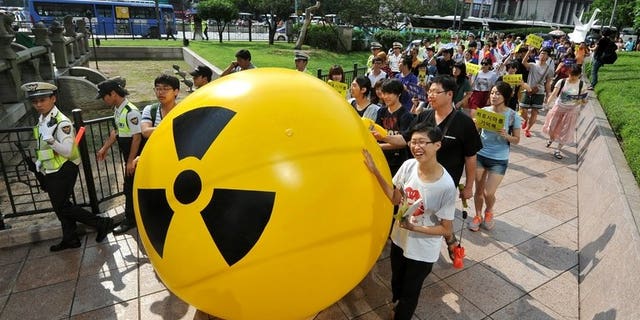 South Korean activists march while rolling a large balloon with a radioactivity warning sign during an anti-nuclear protest in Seoul on August 6, 2013. A former deputy minister has been charged with taking bribes as part of a corruption probe into South Korea's nuclear industry which has already indicted nearly 100 people, prosecutors said Tuesday.