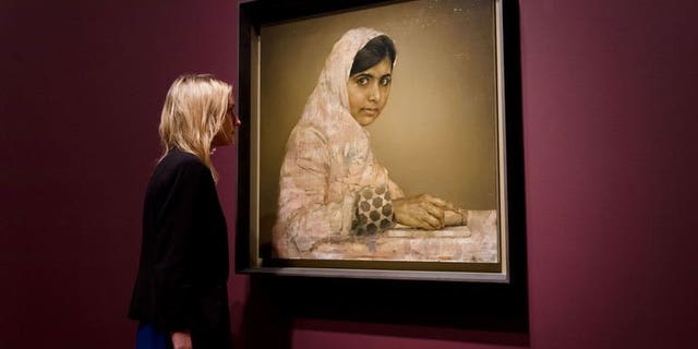 A gallery worker poses with a painted portrait of Malala Yousafzai, the teenage Pakistani advocate for girls education who was shot in the head by the Taliban in 2012, by Jonathan Yeo at the National Portrait Gallery in central London on September 10, 2013.