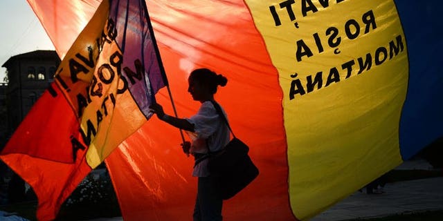 A protester holds a flag reading "Save Rosia Montana" during demonstrations in Bucharest against the Rosia Montana Gold Corporation (RMGC), a Canadian gold mine project using cyanide,on September 8, 2013.