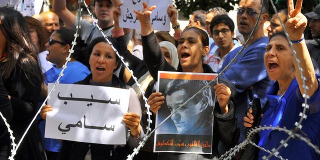 Demonstrators hold pictures of Sami El-Fehri, jailed boss of the Ettounsiya TV channel, as they shout slogans calling for his release outside the court in Tunis on April 15, 2013.