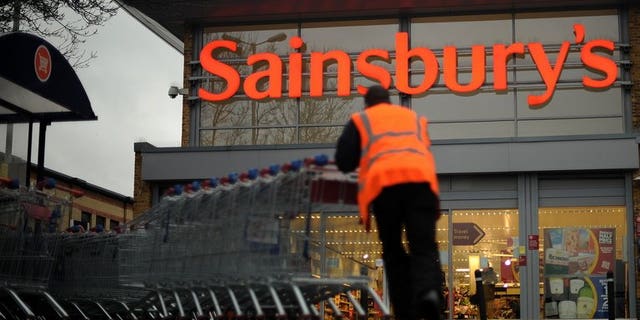 An employee moves shopping trolleys in front of a Sainsbury's store in London, on January 12, 2011. Sainsbury's has issued a recall of all of its bagged watercress and salads containing watercress due to an outbreak of E. coli.