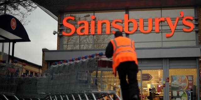 An employee moves shopping trolleys in front of a Sainsbury's store in London, on January 12, 2011. Sainsbury's has issued a recall of all of its bagged watercress and salads containing watercress due to an outbreak of E. coli.
