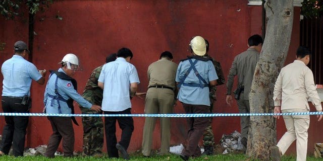 Bomb officials and police inspect a home-made bomb near Cambodia's parliament in Phnom Penh on September 13, 2013. The makeshift bomb was safely detonated by explosive experts, causing a loud bang that shook some nearby buildings, police said.