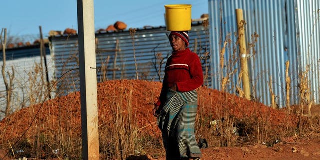 A woman brings water to her shack as workers who support the National Union of Mineworkers start a strike in Carletonville on September 3, 2013. South African construction workers have ended a three week strike after reaching a 12 percent wage hike deal with employers, their union said on Friday.