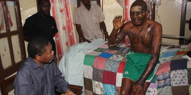 Zanzibar President Ali Mohamed Shein (Bottom L) consoles Roman Catholic priest Joseph Anselm Mwangamba (R) as he is treated at the Mnazi Mmoaj Hospital, Zanzibar's main hospital in the Stone Town, on September 14, 2013.