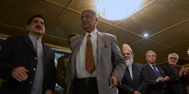 Former Pakistani nuclear scientist and chairman of Tehreek-e-Tahafuz Pakistan party, Abdul Qadeer Khan (2L), stands to give a speech during a public meeting in Islamabad on February 26, 2013.
