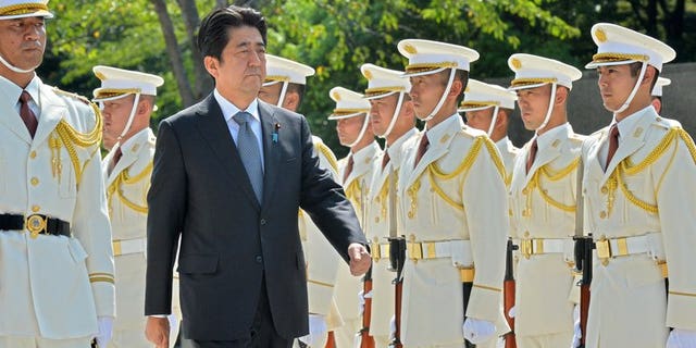 Japanese Prime Minister Shinzo Abe reviews honor guards at the defence ministry in Tokyo on Sept. 12, 2013.