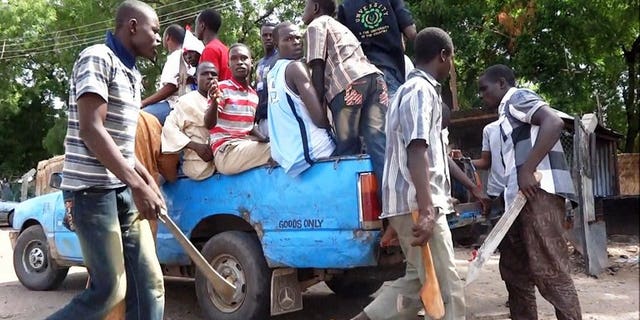 Machete and axe wielding neighbourhood vigilantes hop into a pick-up on July 19, 2013 for an operation to hunt down Boko Haram Islamists in Maiduguri.