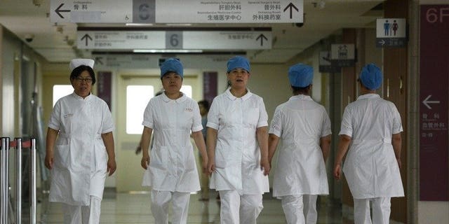 Illustration: a group of nurses walks along a corridor at a hospital in Beijing on July 29, 2013.