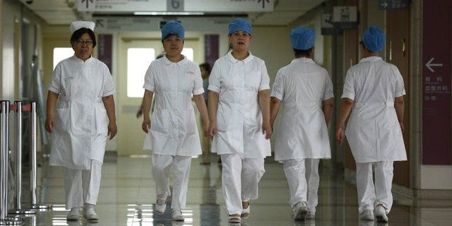 Illustration: a group of nurses walks along a corridor at a hospital in Beijing on July 29, 2013.