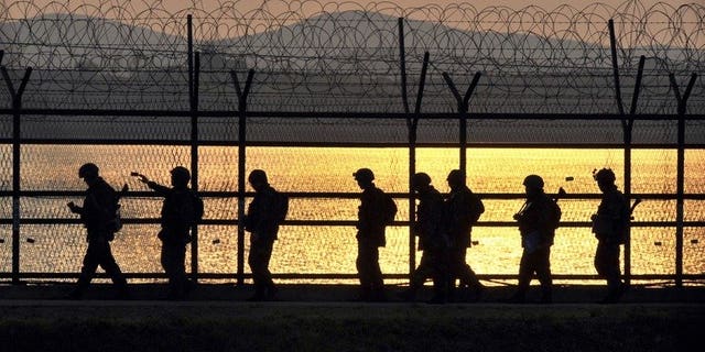 South Korean soldiers patrol along a military fence near the Demilitarized Zone (DMZ) dividing the Korean peninsula near the border city of Paju, on April 26, 2013. South Korean troops have fatally shot a man trying to swim across a border river into North Korea on Monday, after he ignored warnings, a defence ministry spokesman told AFP.