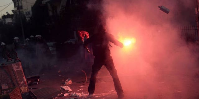 A Greek protester lights a flare during clashes with riot policemen in Athens on September 18, 2013.
