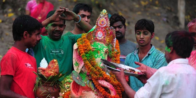 Indian devotees prepare to dip a statue of the Hindu god Ganesha in the confluence of the Yamuna and Ganges river, near Allahabad on September 15, 2013. Nine people have drowned in India's capital during religious festivals that involve immersing statues of Hindu gods in a river.