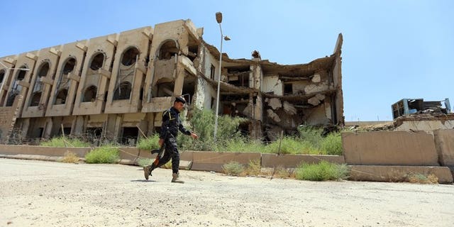 A security officer passes the destroyed former United Nations headquarters in Baghdad on August 16. The bodies of 10 young men shot in the head or chest were found on Thursday in a disused factory in the Iraqi capital, security and morgue official said.