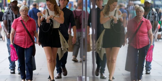 Shoppers are reflected in windows as they walk past a shop on Oxford Street in London on August 7, 2013. British retail sales fell unexpectedly in August after unusually hot weather in July had fuelled spending on food, drinks and summer clothing, official data has shown.