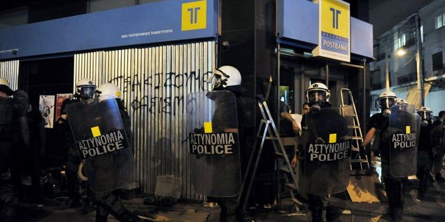 Greek riot police pass a graffiti slogan reading 'smash fascism' during a demonstration against fascism and Neo-Nazis in an Athens suburb, on September 19, 2013. The suspected killer of an anti-fascist musician, whose stabbing sparked nationwide protests and raised social tensions in the debt-wracked country, has appeared in a Piraeus courthouse under heavy security.