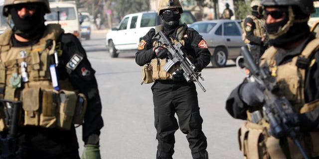 Iraqi anti-terror police stand guard at a checkpoint in Baghdad, on January 6, 2011. At least four police officers have been killed after suicide bombers attacked their base in Baiji, according to a fellow officer and a doctor.