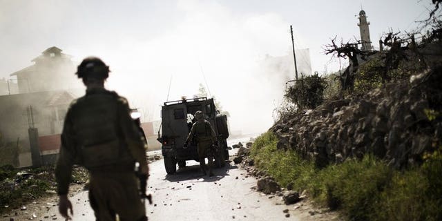 Israeli soldiers walk toward a cloud of tear gas during clashes with Palestinian stone throwers near the West Bank city of Hebron, on April 3, 2013. A Palestinian has abducted and killed an Israeli soldier whose body was found in the north of the occupied West Bank, according to the military.