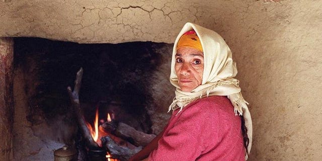 A woman who has never known gas or electricity warms herself 19 February 2001 by a fire in a makeshift home in Cherrata, 100 kms south of Algiers. General Electric Co. has won a $2.2 billion contract to provide turbines for six power plants in Algeria, state energy giant Sonatrach announced on Sunday.
