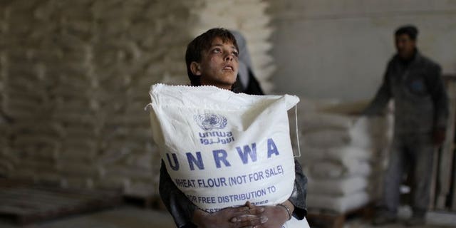 A Palestinian boy holds a sack of flour at a United Nations Relief and Works Agency (UNRWA) aid distribution centre in Gaza City, on April 10, 2013. Israel has answered EU anger over the confiscation of humanitarian aid for Palestinians with accusations diplomats at the scene defied a court order and one struck a policeman.