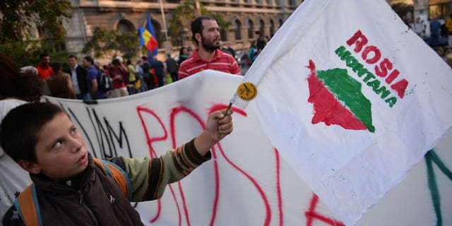 A child waves a flag with the logo of "Save Rosia Montana" NGO during the 22nd day of demonstrations in Bucharest against the Rosia Montana Gold Corporation (RMGC), a Canadian gold mine project using cyanide, on September 22, 2013.