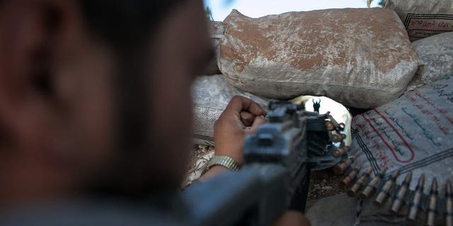 A Syrian rebel fighter points his rifle through a hole in sandbags on June 14, 2013 in Idlib.