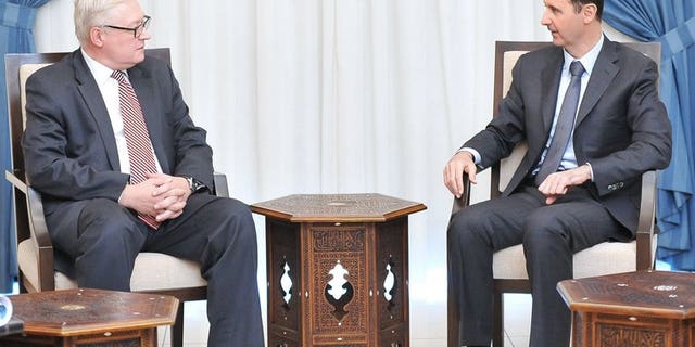 A Syrian Arab News Agency (SANA) handout from September 18, 2013 shows Russian Deputy Foreign Minister Sergei Ryabkov (left) and Syrian President Bashar al-Assad, Damascus. A UN Security Council resolution on Syria could mention Chapter VII of the UN Charter which allows force or tough sanctions, a top Russian diplomat said Tuesday.