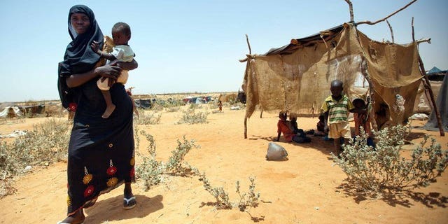 A handout from the United Nations-African Union Mission in Darfur on May 22, 2013 shows a Sudanese woman walking with her baby at the new settlement of the Zam Zam camp for Internally Displaced Persons (IDP), in North Darfur. Demonstrators protesting fuel price hikes torched the headquarters of Sudan's ruling National Congress Party in Khartoum's twin city Omdurman on Tuesday, witnesses said.