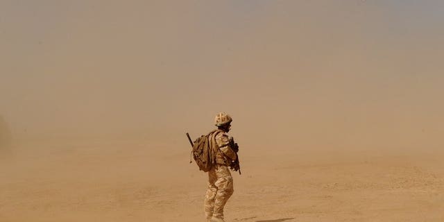 A British soldier walks near the Pimon military camp in Nad-e Ali district of Helmand province on March 25, 2010.