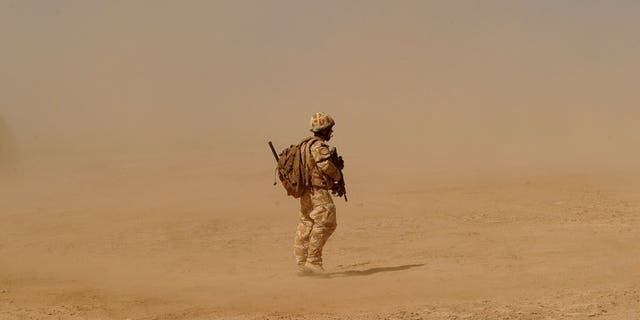A British soldier walks near the Pimon military camp in Nad-e Ali district of Helmand province on March 25, 2010.
