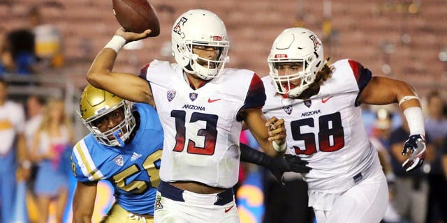 Arizona quarterback Brandon Dawkins (13) passes under pressure from UCLA defensive lineman Deon Hollins (58), left, with protection from Arizona offensive lineman Layth Friekh (58), right, in the first half of an NCAA college football game Saturday, Oct. 1, 2016, in Pasadena, Calif. UCLA won, 45-24. (AP Photo/Reed Saxon)