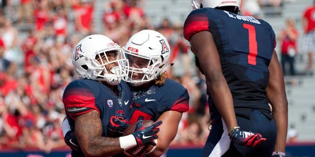 Oct 10, 2015; Tucson, AZ, USA; Arizona Wildcats running back Orlando Bradford (21) is congratulated by offensive lineman Layth Friekh (58) and wide receiver Cayleb Jones (1) after scoring a touchdown during the second quarter against the Oregon State Beavers at Arizona Stadium. Mandatory Credit: Casey Sapio-USA TODAY Sports