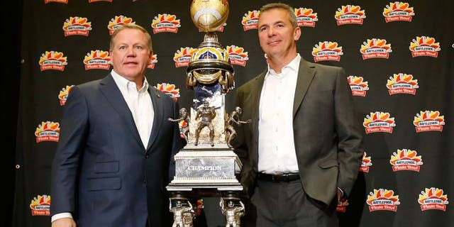 Notre Dame head coach Brian Kelly, left, and Ohio State head coach Urban Meyer pose with the trophy during a news conference for the Fiesta Bowl NCAA college football game, Thursday, Dec. 31, 2015, in Scottsdale, Ariz. Notre Dame plays Ohio State on New Year's Day. (AP Photo/Rick Scuteri)