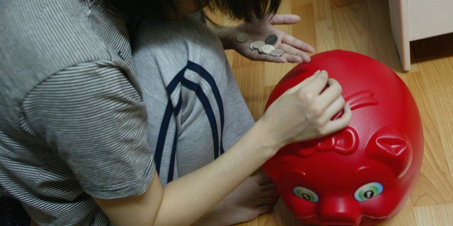 SEOUL, SOUTH KOREA - OCTOBER 19: A South Korean prostitute deposits her money into a piggy-bank in her room on October 19 2004, in Seoul, South Korea. The South Korean government began enforcing new laws last month to target human traffickers, pimps and prostitutes. The sex industry accounts for more than four percent of South Korea's gross domestic product (GDP), with its annual sales estimated at 24 trillion won (21 billion dollars) last year. Statistics show one in five South Korean men buy sex four times a month and 4.1 percent of women aged 20 to 30 rely on prostitution to make a living. (Photo by Chung Sung-Jun/Getty Images)