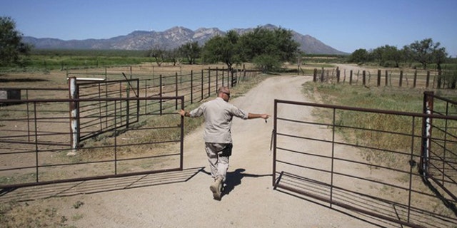 A Border Patrol agent opens a gate leading to a dirt road as he searches for illegal immigrants in the dessert of Pima County, Ariz., Aug. 17, 2009. (Reuters Photo)