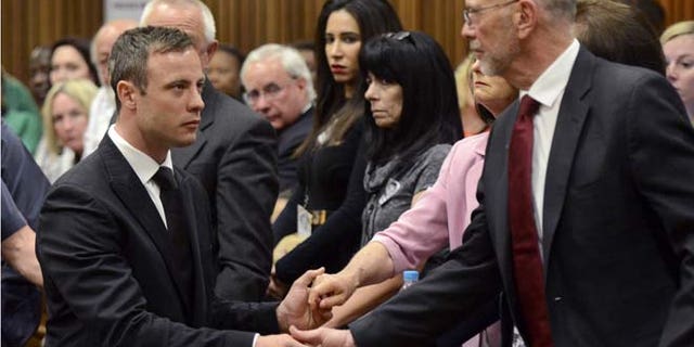 Oct. 21, 2014: Oscar Pistorius, left, greets his uncle Arnold Pistorius, right, and other family members as he is led down to the cells of the court in Pretoria.