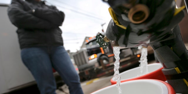 Feb. 1, 2017: Ronette Cooley watches as she fills containers with water at a city fire station in the Lawrenceville section of Pittsburgh.