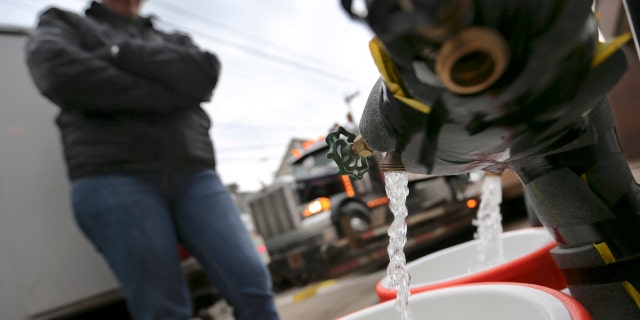 Feb. 1, 2017: Ronette Cooley watches as she fills containers with water at a city fire station in the Lawrenceville section of Pittsburgh.