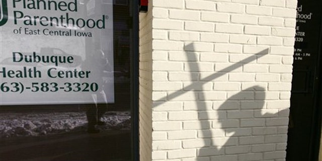 In this Jan. 22, 2009, file photo, the shadow of an anti-abortion activist holding a cross can be seen near a Planned Parenthood in Dubuque, Iowa.