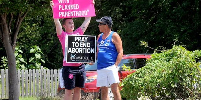 FILE -- July 28, 2015: Andrew Ward, left, and Bill Pauls discuss their positions on abortion during a rally across the street from the Planned Parenthood of Kansas and Mid-Missouri in Columbia, Mo. (Don Shrubshell/Columbia Daily Tribune via AP)