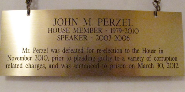 The plaque hanging in the Pennsylvania Capitol below the official portrait of former House Speaker John Perzel and three other former top state lawmakers in Harrisburg, Pa., now includes information about their criminal histories. Plaques that add those details to the dates the four men served were hung Tuesday, July 15, 2014. (AP Photo/Marc Levy)