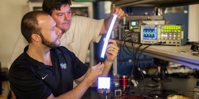 Researchers have made a new glowing plastic material that they've formed into lights of different shapes. Here, physicist David Carroll (front) and graduate student Greg Smith (behind) with a few of their creations.