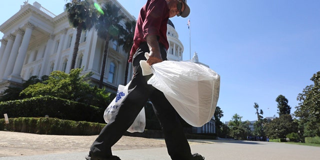Aug. 12, 2014: File photo, a man carries plastic single-use bags past the State Capitol in Sacramento, Calif.