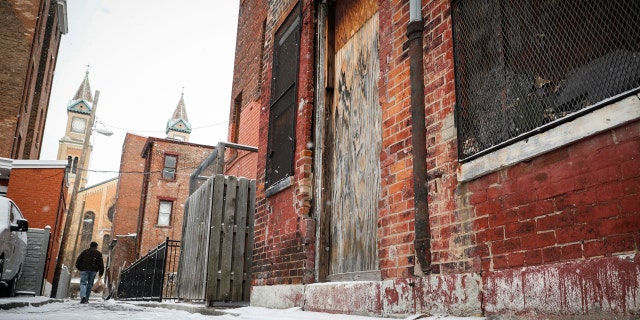 Pedestrians pass boarded up buildings in downtown Cincinnati, Thursday, Jan. 5, 2017.
