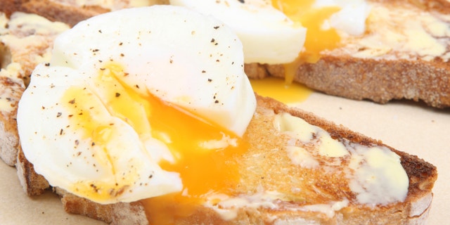 Poached eggs on buttered toast from a rustic white bread loaf.