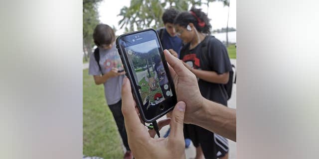 Pinsir, a Pokemon, is found by a group of Pokemon Go players at Bayfront Park in downtown Miami on July 12, 2016, as the "Pokemon Go" craze has sent legions of players hiking around cities and battling with "pocket monsters" on their smartphones. (AP Photo/Alan Diaz)