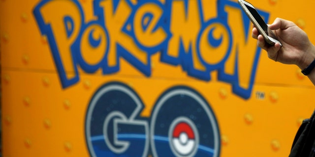 File photo: A man uses a mobile phone in front of an advertisement board bearing the image of Pokemon Go at an electronic shop in Tokyo, Japan, July 27, 2016. (REUTERS/Kim Kyung-Hoon)