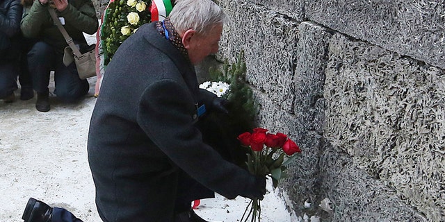 A holocaust survivor places flowers in commemoration of the people killed by the Nazis at the former Auschwitz Germany Nazi death camp in Oswiecim, Poland, Friday, Jan. 27, 2017, on the International Holocaust Remembrance Day that marks the liberation of the Auschwitz Nazi death camp on Jan. 27, 1945.(AP Photo/Czarek Sokolowski)